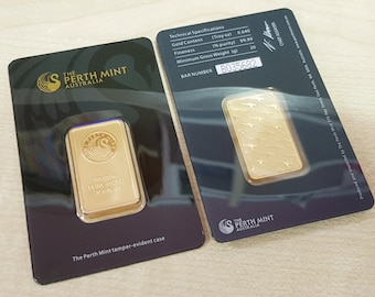 Puede incluir: Dos lingotes de oro de The Perth Mint, Australia, presentados en tarjetas negras. Una barra tiene un logotipo y texto, la otra un diseño de canguro. Las tarjetas muestran especificaciones técnicas y un número de barra.