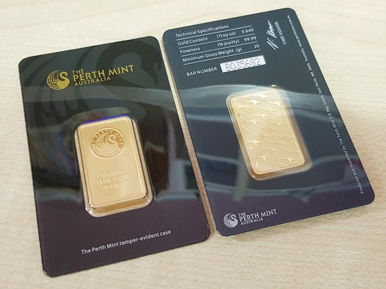 Puede incluir: Dos lingotes de oro de The Perth Mint, Australia, presentados en tarjetas negras. Una barra tiene un logotipo y texto, la otra un dise&ntilde;o de canguro. Las tarjetas muestran especificaciones t&eacute;cnicas y un n&uacute;mero de barra.