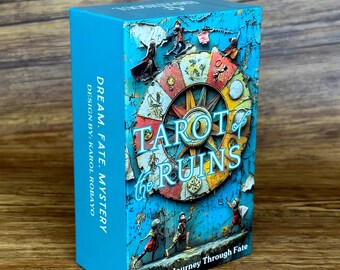 May include: A rectangular deck box for Tarot of the Ruins cards with a bright blue background. The front features a colorful circular wheel design with small figures and the title text. The side panel reads Dream. Fate. Mystery. Design by: Karol Robayo.