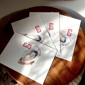 Peut inclure: Quatre impressions d'art rectangulaires blanches présentant une illustration détaillée à l'aquarelle d'une coquille d'huître avec un intérieur bleu. Chaque impression affiche un petit tampon rectangulaire rouge avec le texte REEN au-dessus.