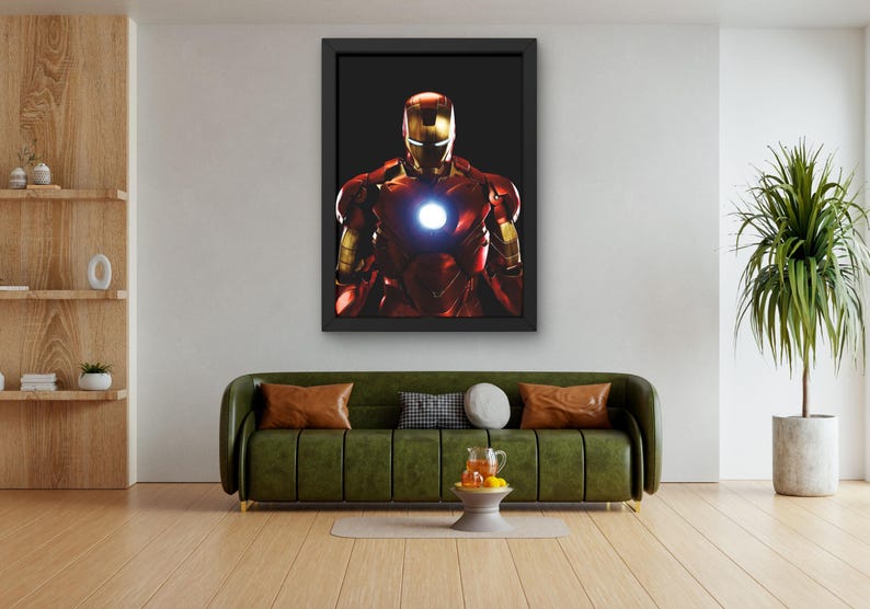 以下が含まれることがあります： アイアンマンの象徴的な赤と金のアーマーを着た、光る胸部を備えた額入りのアートワーク。画像は黒い背景に配置され、印象的なコントラストを生み出しています。アートワークは緑色のソファの上に飾られています。
