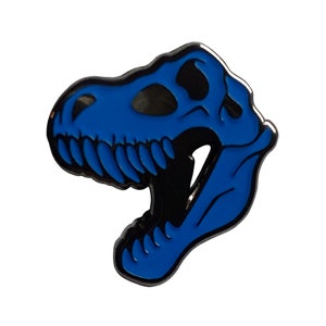 May include: Blue enamel pin of a Tyrannosaurus Rex skull. The pin is a detailed silhouette of the dinosaur's head with a black outline and a blue enamel fill.