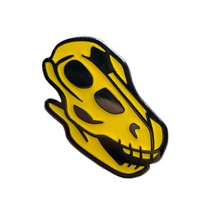 May include: Yellow enamel dinosaur skull pin with black outline.