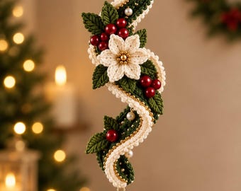 May include: A hanging decorative ornament featuring a wavy, crocheted structure in cream and dark green yarn. It is adorned with a central cream-colored flower, dark green leaves, small red berries, and white pearls, ending in a clear crystal drop.