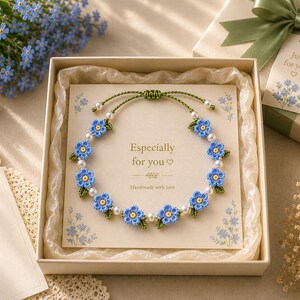 May include: A blue floral bracelet with white pearls and green detailing is presented in a gift box. The box includes a card with the text "Especially for you" and "Handmade with love". A gift tag with "Just for you" is attached.