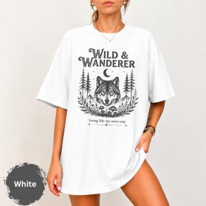 Maglietta Wild & Wanderer con lupo, T-shirt per amanti della natura, T-shirt grafica boho con lupo, T-shirt per avventure nella foresta, Regalo per escursioni all'aperto, T-shirt per amanti della fauna selvatica