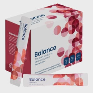 Puede incluir: Una caja de mezcla para bebidas con sabor a frutos rojos "Balance" con un sobre a juego. La caja es blanca con dise&ntilde;os circulares rojos y rosas. La palabra "Balance" est&aacute; en azul en el sobre y en la caja.