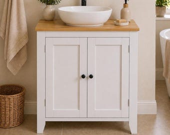 Mueble de baño blanco con lavabo sobre encimera, estilo rústico, con encimera de madera, independiente, para espacios pequeños.