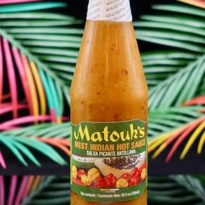 May include: A bottle of Matouk's West Indian Hot Sauce. The label is green with yellow text and features a papaya and chili pepper illustration. The bottle is filled with a thick, orange sauce and sealed with a white top.