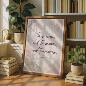 Peut inclure: Une affiche encadrée présentant le texte To-morrow, and To-morrow, and To-morrow, suivi du nom William Shakespeare. Le design comprend des formes abstraites à l'aquarelle dans des tons de rose, beige et brun sur un fond clair.