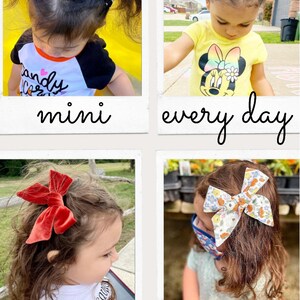 Pu&ograve; includere: Quattro immagini di bambini con fiocchi per capelli di diversi stili e colori. I fiocchi includono bianco e nero, velluto rosso e motivi floreali. Il testo "mini", "every day", "large" e "jumbow" &egrave; scritto sotto ogni immagine.