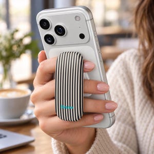 May include: A silver smartphone with a vertical black and white striped phone grip attached to the back. The grip features the word Eleanor printed in small teal letters near the bottom edge. The device has a triple camera array on the top left.