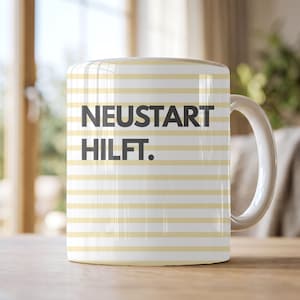 Könnte beinhalten: Ein weißer Keramikbecher mit horizontalen hellgelben Streifen und dem dunkelgrauen Text NEUSTART HILFT. Der Becher hat einen glatten zylindrischen Körper und einen geschwungenen Henkel auf der rechten Seite für heiße oder kalte Getränke.