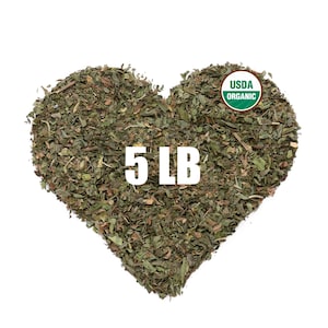 May include: A heart-shaped pile of dried green herbs with the text 5 LB printed in white in the center and a circular green and white USDA ORGANIC seal in the upper right corner. The herbs consist of small, fragmented dark and light green leaves.