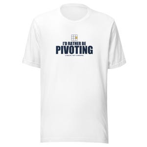 May include: A white short-sleeve t-shirt featuring a graphic with a small grid icon and the text I'D RATHER BE PIVOTING (TABLES, NOT CAREERS) in dark blue lettering. The design is centered on the chest of the shirt, which has a crew neckline.