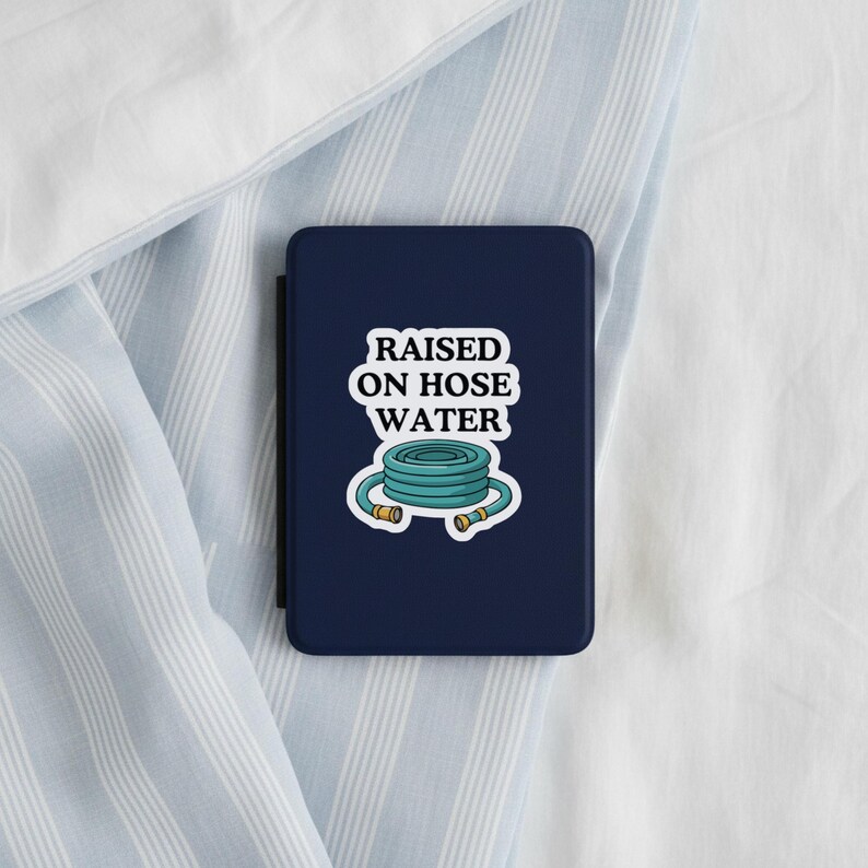 Op de afbeelding: Een donkerblauwe rechthoekige e-readerhoes met een witte sticker met de tekst RAISED ON HOSE WATER in zwarte letters boven een grafische illustratie van een opgerolde blauwgroene tuinslang met goudkleurige metalen koppelingen.