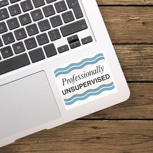 May include: A rectangular sticker featuring the text Professionally UNSUPERVISED in black serif and sans-serif fonts. The background consists of horizontal wavy stripes in alternating shades of muted blue, cream, and light tan colors.