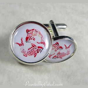 May include: A pair of silver cufflinks with red and white koi fish designs. The cufflinks are round and have a white background with red koi fish swimming in a circle.