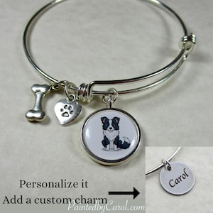 May include: Silver-toned charm bracelet with a dog-themed design. It features a bone charm, a heart charm with a paw print, and a round charm with a black and white dog illustration. The text "Personalize it, Add a custom charm" is visible.