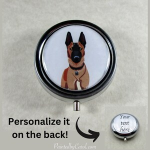 May include: A silver round pill box with a white background and a cartoon image of a brown and black German Shepherd dog. The back of the pill box is silver and can be personalized with text.