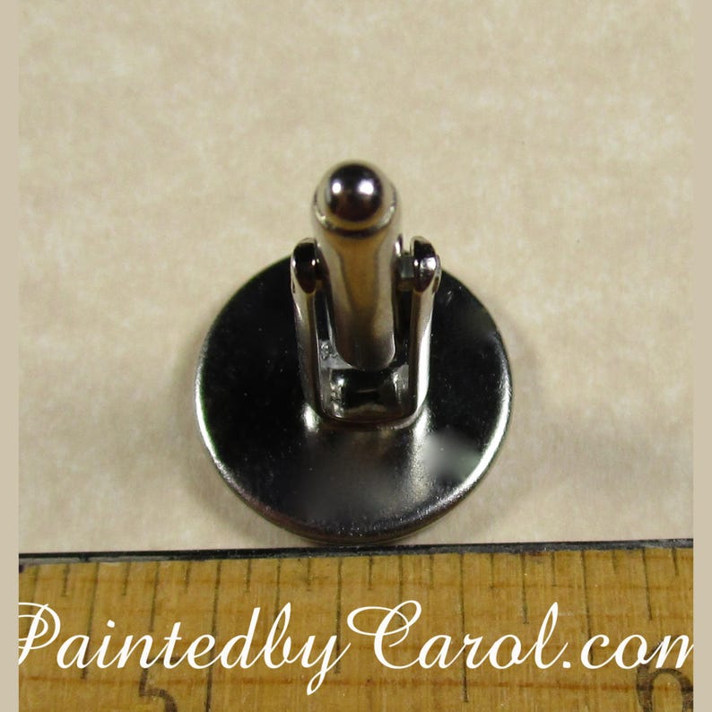 May include: Silver cufflinks with a round, silver-toned face. The cufflinks have a hinged back.