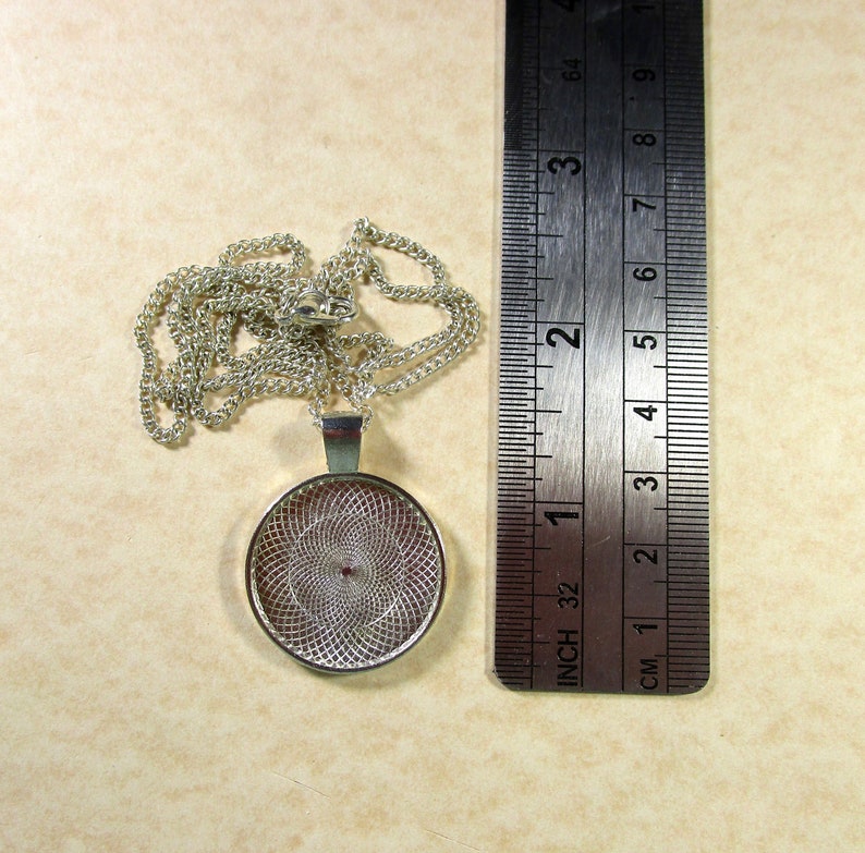 May include: Silver pendant necklace with a round, silver, decorative, openwork design. The pendant is approximately 1 inch in diameter. The necklace is approximately 18 inches long.