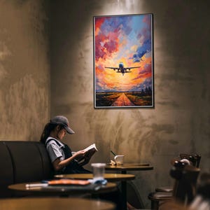 Pode incluir: Uma impressão de arte de parede retangular apresentando um avião comercial em voo contra um céu vibrante ao pôr do sol com tons de laranja, rosa e azul, acima de uma paisagem com uma estrada que leva ao horizonte sob a aeronave.