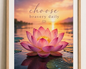 May include: Framed art print featuring a pink lotus flower floating on water. The image has a sunset backdrop with the words "choose bravery daily" in elegant script. The artwork is in a wooden frame.