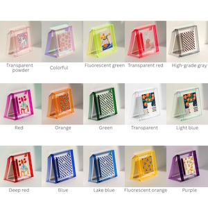 May include: A collection of fifteen rectangular acrylic photo frames in various colors including transparent, red, green, blue, orange, purple, and gray. Each frame features a slanted stand and holds a small decorative card with unique graphic prints.