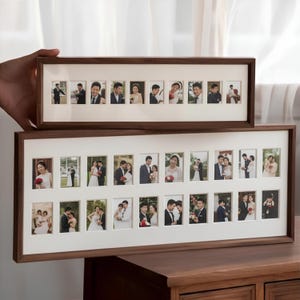 Op de afbeelding: Twee rechthoekige houten fotolijsten, de ene boven de andere, elk met meerdere kleine foto's. De lijsten hebben een donkerbruine afwerking en witte passe-partouts. De foto's lijken van een bruiloft te zijn.