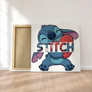 May include: A canvas art print featuring the character Stitch from Lilo & Stitch. Stitch, in shades of blue, is holding a red heart with the word "STITCH" across it. The canvas is displayed on a white wall with a wooden frame.