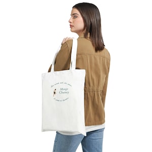 May include: White tote bag with the text "Mango Chutney" in a circular design, along with the phrase "It's sweet and it's sour, I want to devour." The bag has white straps and is being carried over the shoulder.