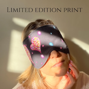 May include: A black sleep mask with a colorful heart design and the text "LIMITED EDITION PRINT". The heart is made up of small, colorful shapes. The mask also features pink and blue dots.