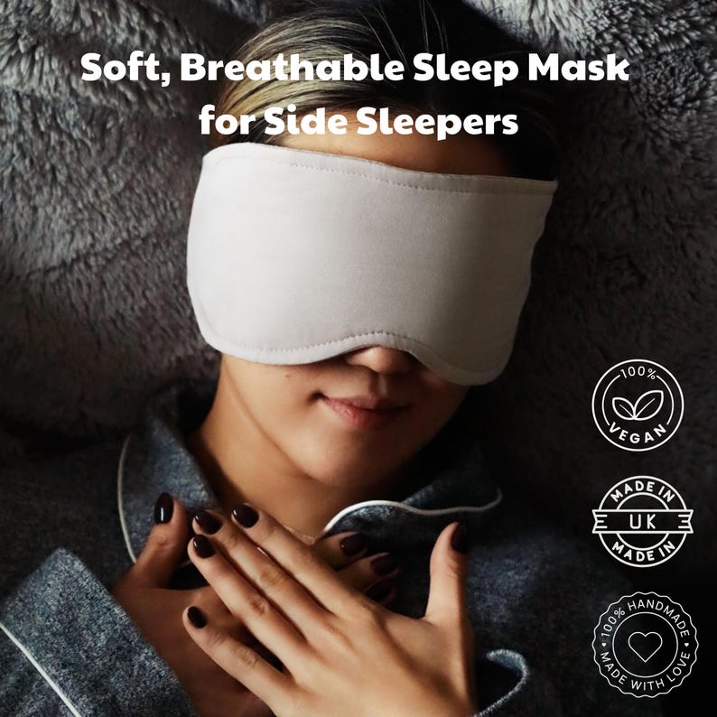 Puede incluir: Una m&aacute;scara para dormir de color beige claro cubre los ojos de una persona. La m&aacute;scara est&aacute; hecha de un material suave y transpirable, dise&ntilde;ada para personas que duermen de lado. El texto en la imagen dice "Soft, Breathable Sleep Mask for Side Sleepers". La imagen tambi&eacute;n incluye etiquetas veganas y hechas a mano.