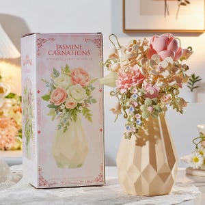 May include: A beige geometric vase holds a bouquet of paper flowers in shades of pink, white, and green. The vase is next to a box with the words "JASMINE CARNATIONS" and a similar floral arrangement illustration.