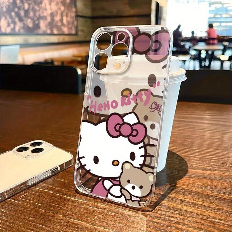 Puede incluir: Funda transparente para tel&eacute;fono con dise&ntilde;o de Hello Kitty, con lazo rosa y osito de peluche. La funda tiene la inscripci&oacute;n "Hello Kitty" en rosa. Dise&ntilde;ada para un smartphone.