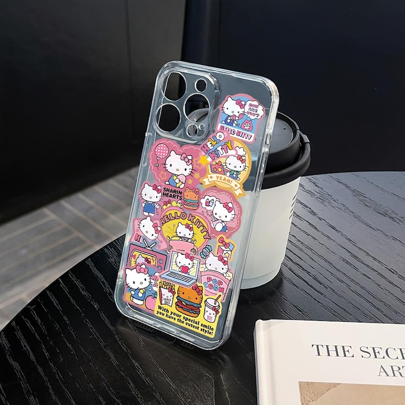 May include: Clear phone case decorated with Hello Kitty stickers in various poses and scenes. The stickers feature pink, white, and yellow accents, with text that reads "HELLO KITTY", "YEAH!", and "With your special smile you have the cutest style!"