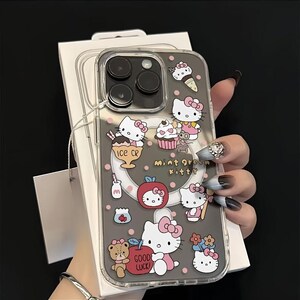 May include: Transparent phone case with a grey background, decorated with Hello Kitty and food illustrations. The case shows ice cream, cupcakes, and apples. Text on the case reads "mint green kitty" and "GOOD LUCK".