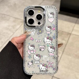 May include: Clear phone case with a sparkly, rhinestone-studded border. The case features multiple Hello Kitty designs in pink and white, with hearts, bows, and flowers. The text "Good day!" and "Hello" are also visible.