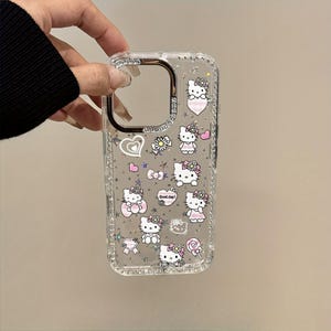 May include: Clear phone case with a glittery border and a design featuring Hello Kitty characters, hearts, flowers, and bows. The case has a rectangular shape with cutouts for the camera and buttons.