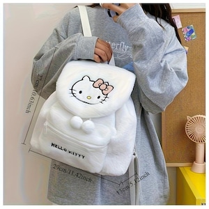 May include: White Hello Kitty backpack with a plush texture. The backpack features a Hello Kitty face with a pink bow and the words "Hello Kitty". It measures 11.42 inches wide, 10.63 inches high, and 5.12 inches deep.
