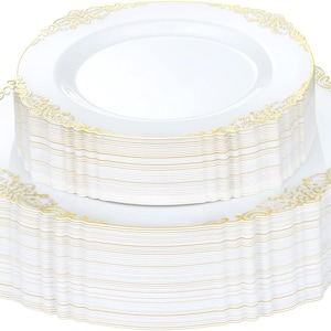 May include: A stack of white round plates featuring a scalloped edge with a gold filigree pattern. The plates are arranged in two distinct piles, with a smaller stack of plates resting on top of a larger stack, both displaying the same gold design.