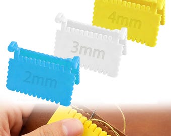 May include: Three plastic stitch spacing gauges in blue, white, and yellow, labelled 2mm, 3mm, and 4mm. A hand uses a yellow gauge to measure stitch spacing on leather. The gauges have a notched edge.