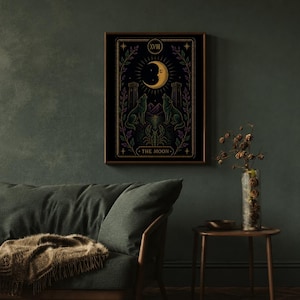 May include: A framed tarot card print featuring a crescent moon, two wolves, and the text "THE MOON." The artwork is in shades of black, gold, green, and purple. The print is displayed on a dark green wall above a green sofa.