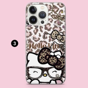 Puede incluir: Una funda transparente para smartphone con un estampado de leopardo en marr&oacute;n y blanco. El dise&ntilde;o incluye el texto Hello Kitty, un personaje grande de Hello Kitty con gafas y lazo de leopardo, y peque&ntilde;os iconos del personaje.