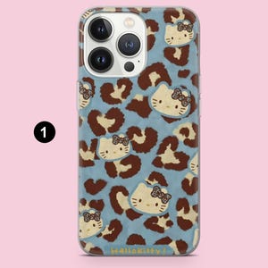 Puede incluir: Una funda transparente para smartphone con un patr&oacute;n repetitivo de caras de Hello Kitty con lazos y manchas de leopardo marrones sobre un fondo azul claro. El texto Hello Kitty est&aacute; impreso en amarillo en la parte inferior de la funda, con recorte.