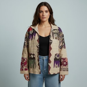 Könnte beinhalten: Eine beige gesteppte Jacke mit einem sich wiederholenden Muster aus stilisierten Elefanten in Lila-, Grün- und Rottönen. Das Kleidungsstück hat einen Kragen, lange Ärmel und eine Vorderöffnung, getragen über einem schwarzen Top und einer hellblauen Jeans.