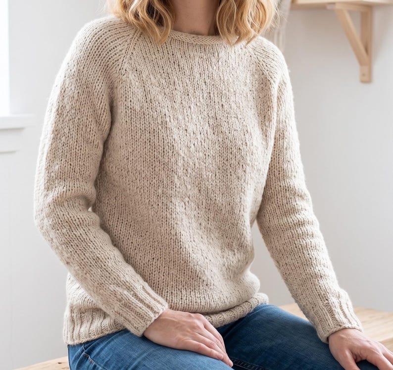 basic knitted raglan sweater beige minimal style
top down seamless knit sweater classic design
close up stockinette knit texture soft yarn detail
woman wearing simple knit sweater everyday outfit
handmade knitted pullover neutral cozy look