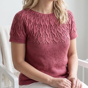 Può includere: Un top in maglia rosa polveroso a maniche corte. Il top presenta un motivo a foglie dettagliato sulla parte superiore del petto e sulle spalle. Le maniche e la parte inferiore del top hanno un design a maglia liscia più semplice. Il top è in materiale morbido e confortevole.