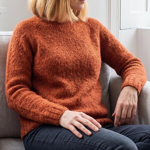 basic knitted raglan sweater beige minimal style
top down seamless knit sweater classic design
close up stockinette knit texture soft yarn detail
woman wearing simple knit sweater everyday outfit
handmade knitted pullover neutral cozy look